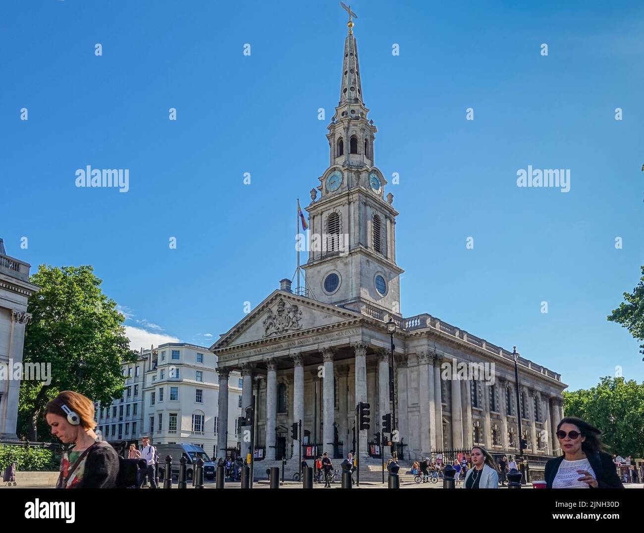 London, UK- July 4, 2022: Trafalgar Square. Entire St. Martin-in-the-fields church against blue sky, Street scene with people, cars, and traffic line. Stock Photo