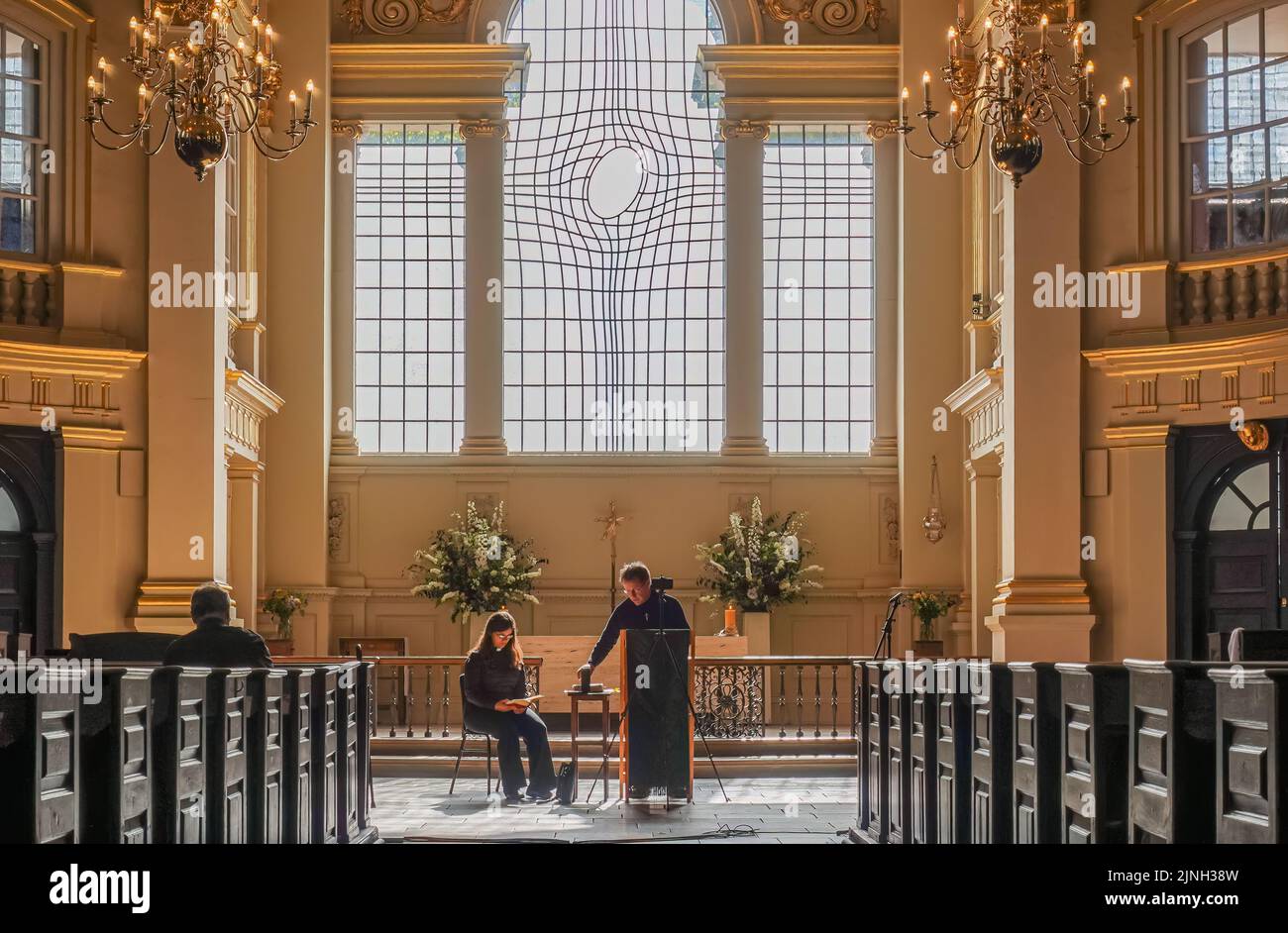 London, UK- July 4, 2022: Off Trafalgar Square. Inside St. Martin-in-the-fields church, Priests in front at chancel under window with smartly designed Stock Photo