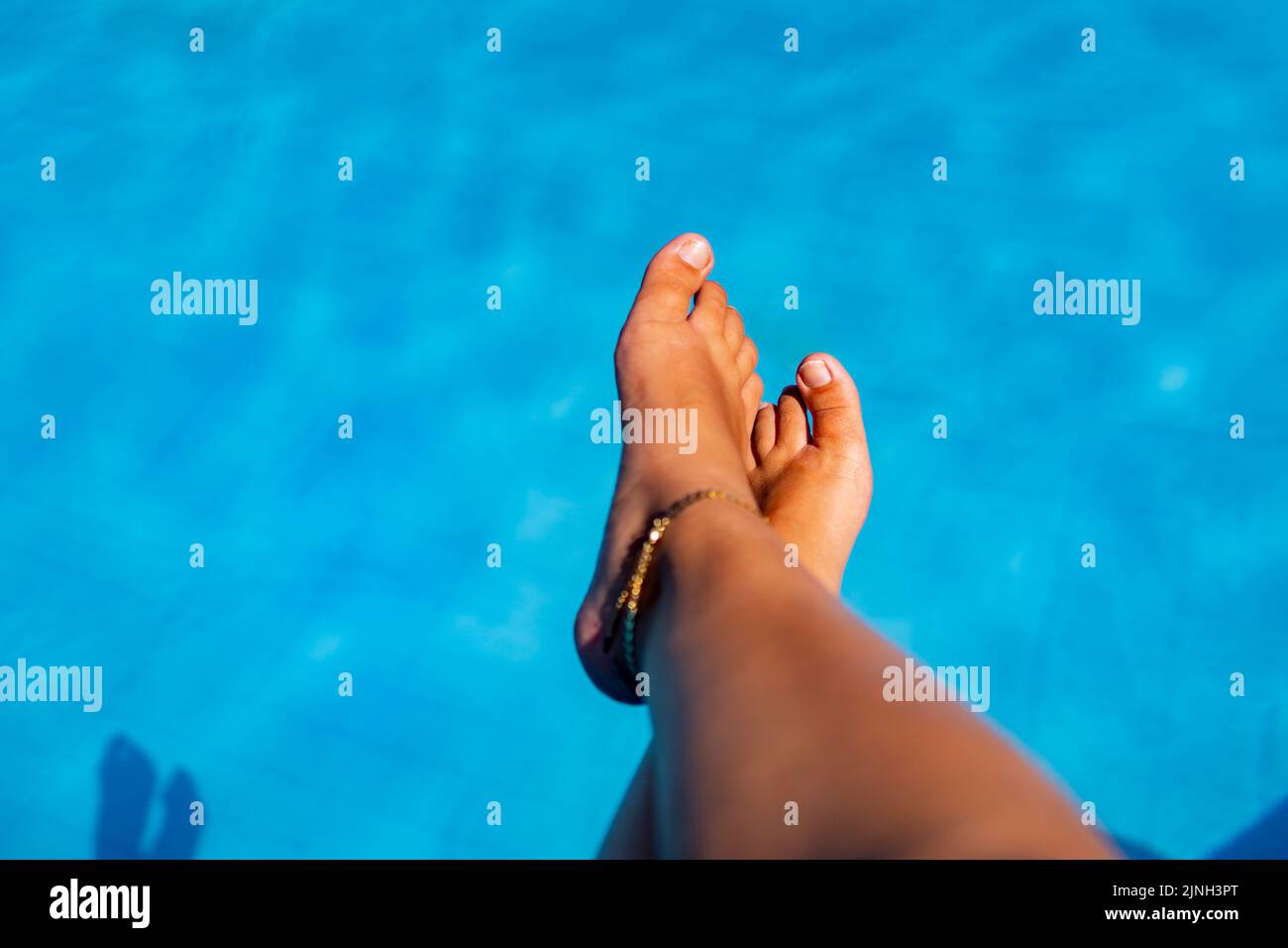 tan wet legs of young woman having summer suntan at swimming pool Stock Photo