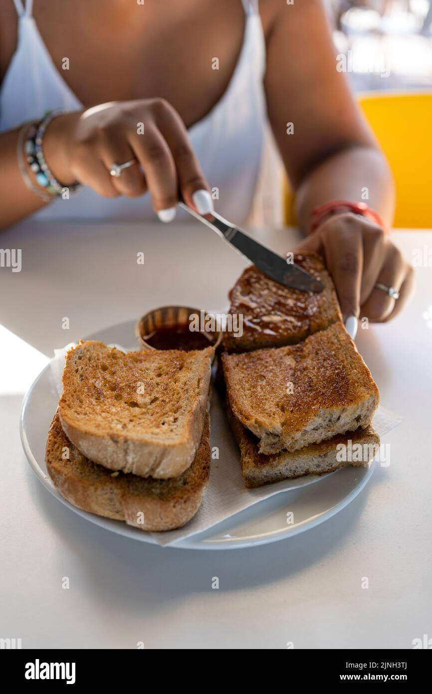 close-up of a woman's hands spreading jam on toast for breakfast in a coffee shop Stock Photo