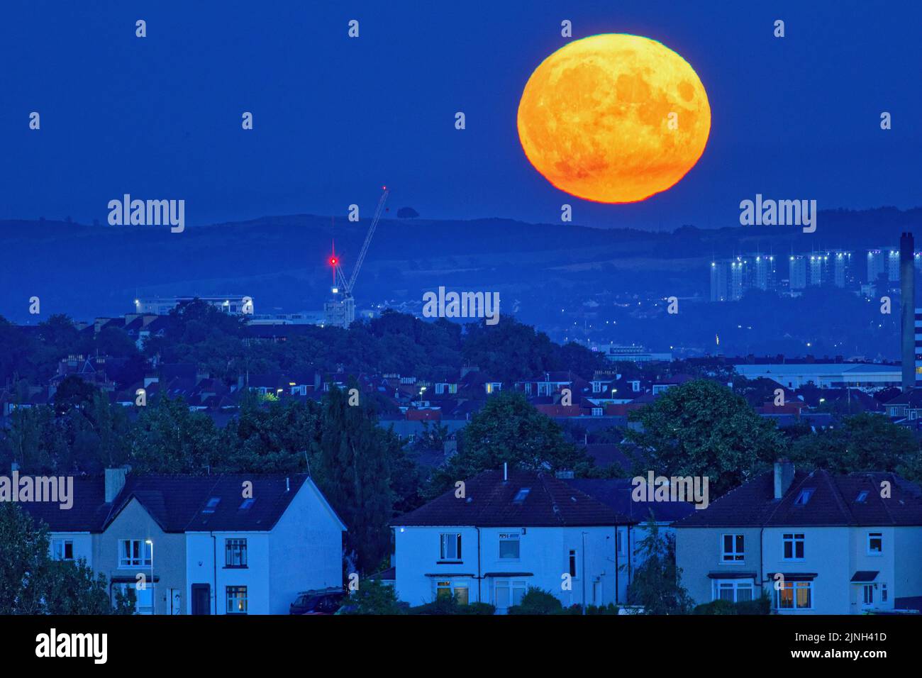 Glasgow, Scotland, UK  11th August,  2022. UK Weather: Sunny weather saw Full sturgeon moon over the south west of the city and the campsie braes hills. Credit Gerard Ferry/Alamy Live News Stock Photo