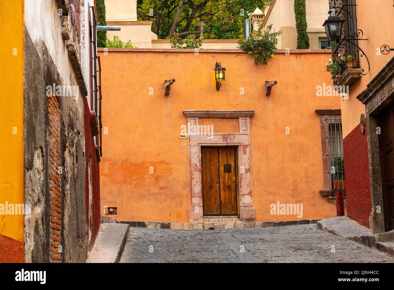 A Mexican style wooden door and colorful facade on a Spanish colonial house on Calle Barranca in the historic city center of San Miguel de Allende, Mexico. Stock Photo