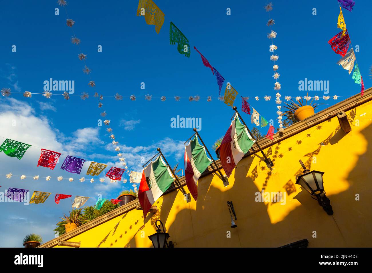 Colorful papel picado fiesta banners and Mexican flags decorate a Spanish colonial style building in the historic city center of San Miguel de Allende, Mexico. Stock Photo