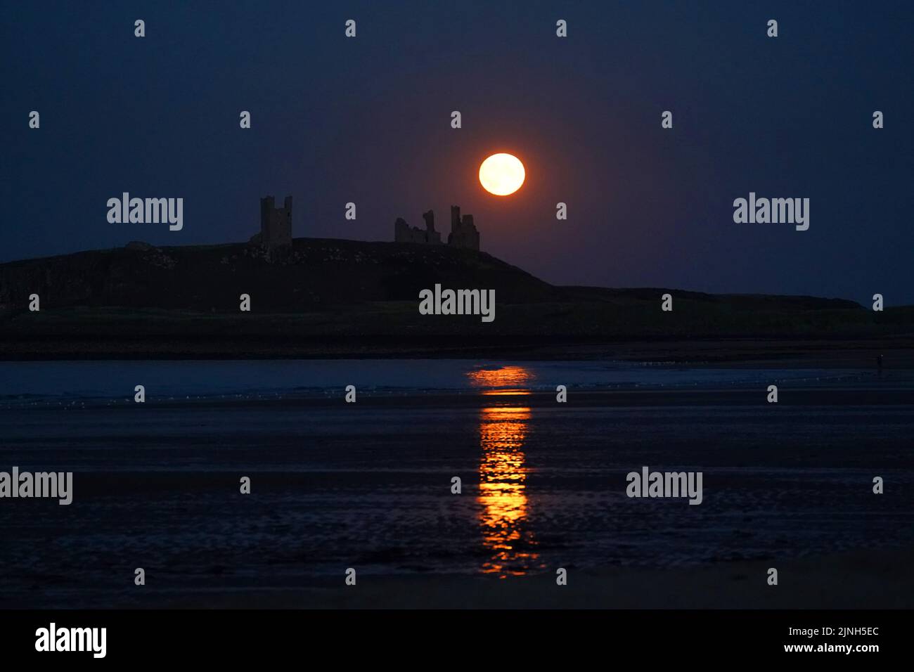 The Sturgeon supermoon, the final supermoon of the year rises over Dunstanburgh Castle in Northumberland. Picture date: Thursday August 11, 2022. Stock Photo