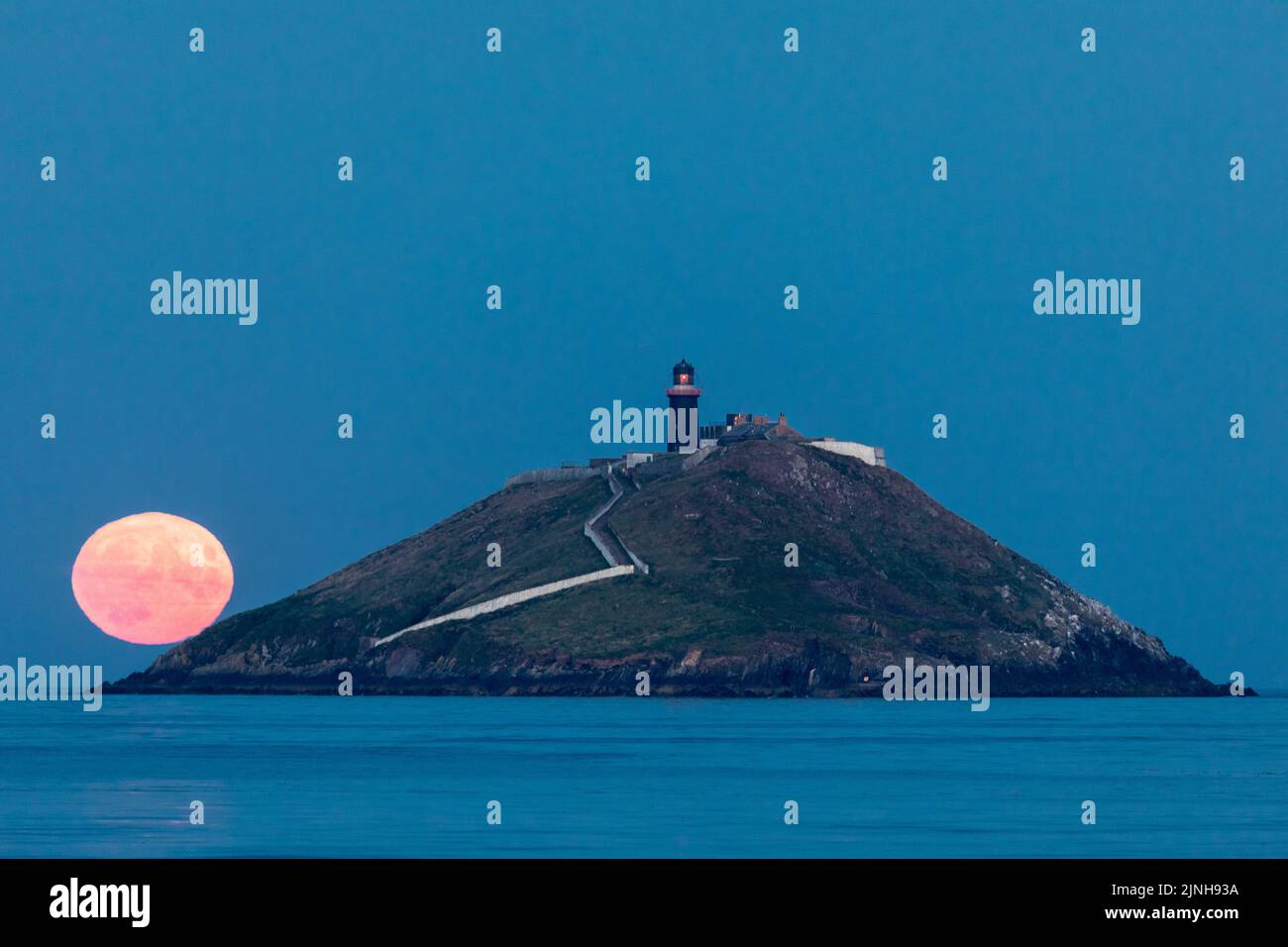 Ballycotton, Cork, Ireland. 11th August, 2022. A Sturgeon Moon rises behind the lighthouse in Ballycotton Bay, Co. Cork, Ireland.  - Credit; David Creedon / Alamy Live News Stock Photo