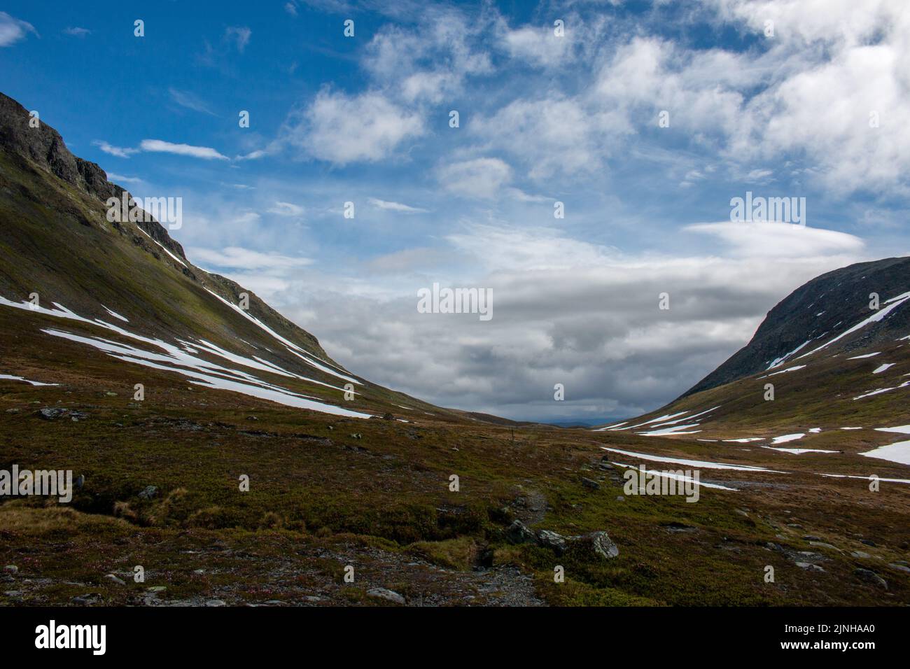 A hiking trail between Norwegian Nedalshytta and Swedish Sylarna mountain stations folowing a valley, early July, Jamtland, Sweden Stock Photo