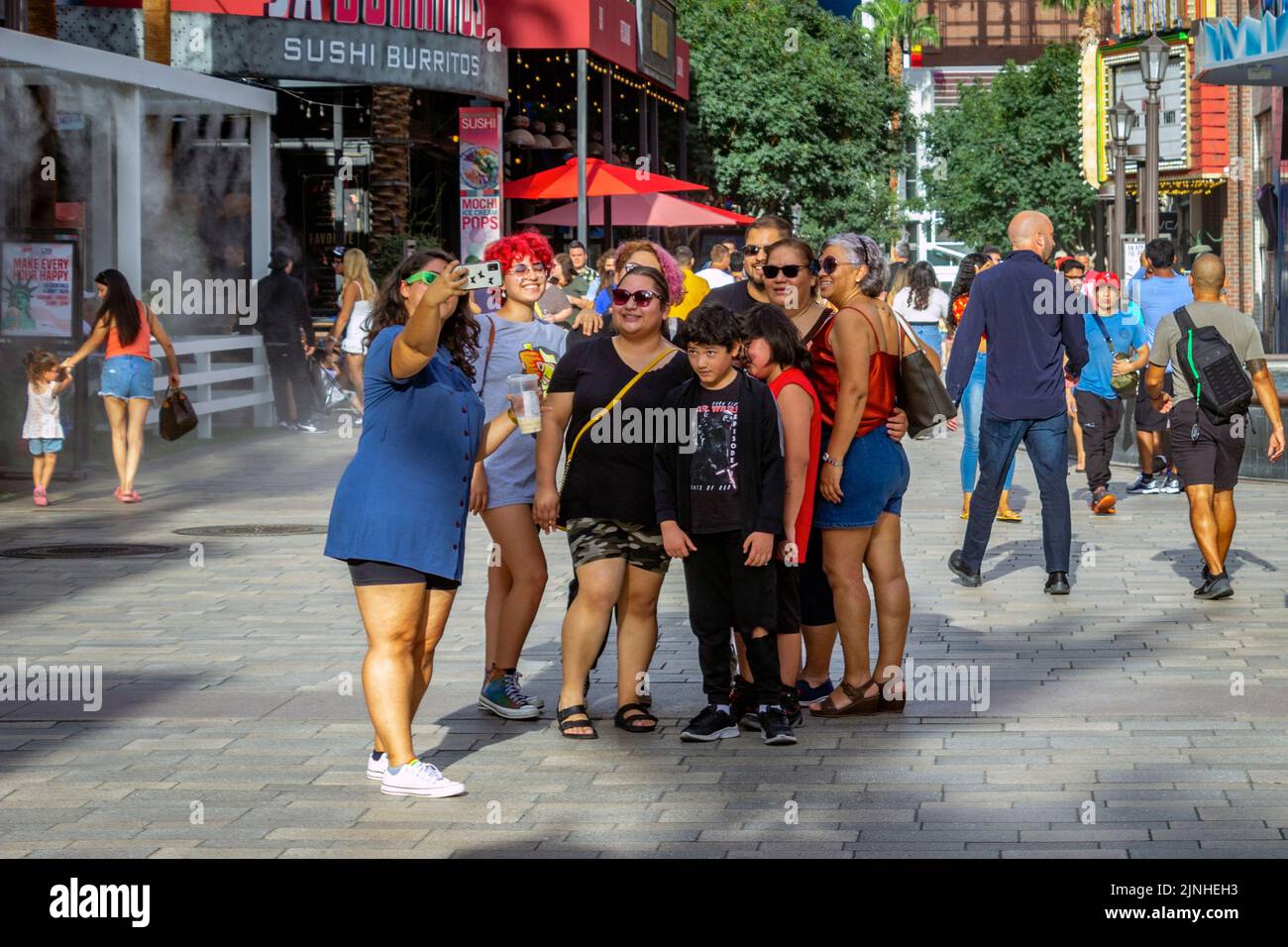 Capture the excitement and energy of Las Vegas with this image of a group of tourists stopping to take photos of themselves at The LINQ Promenade. The Stock Photo