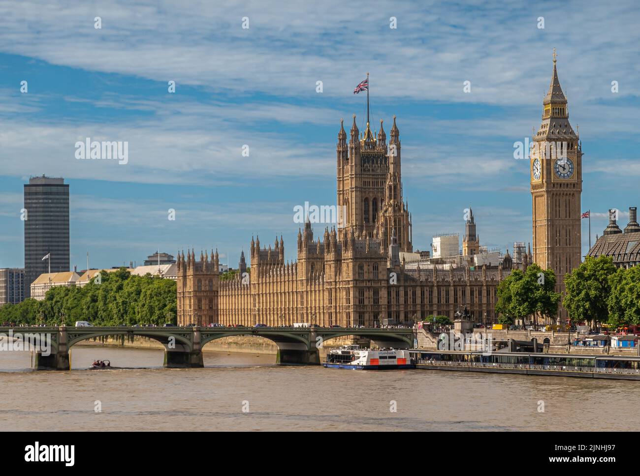 London, UK - July 4, 2022: Scenery with Palace of Westminster, House of Lords, Big Ben, church towers, and further city highrise under blue clludscape Stock Photo