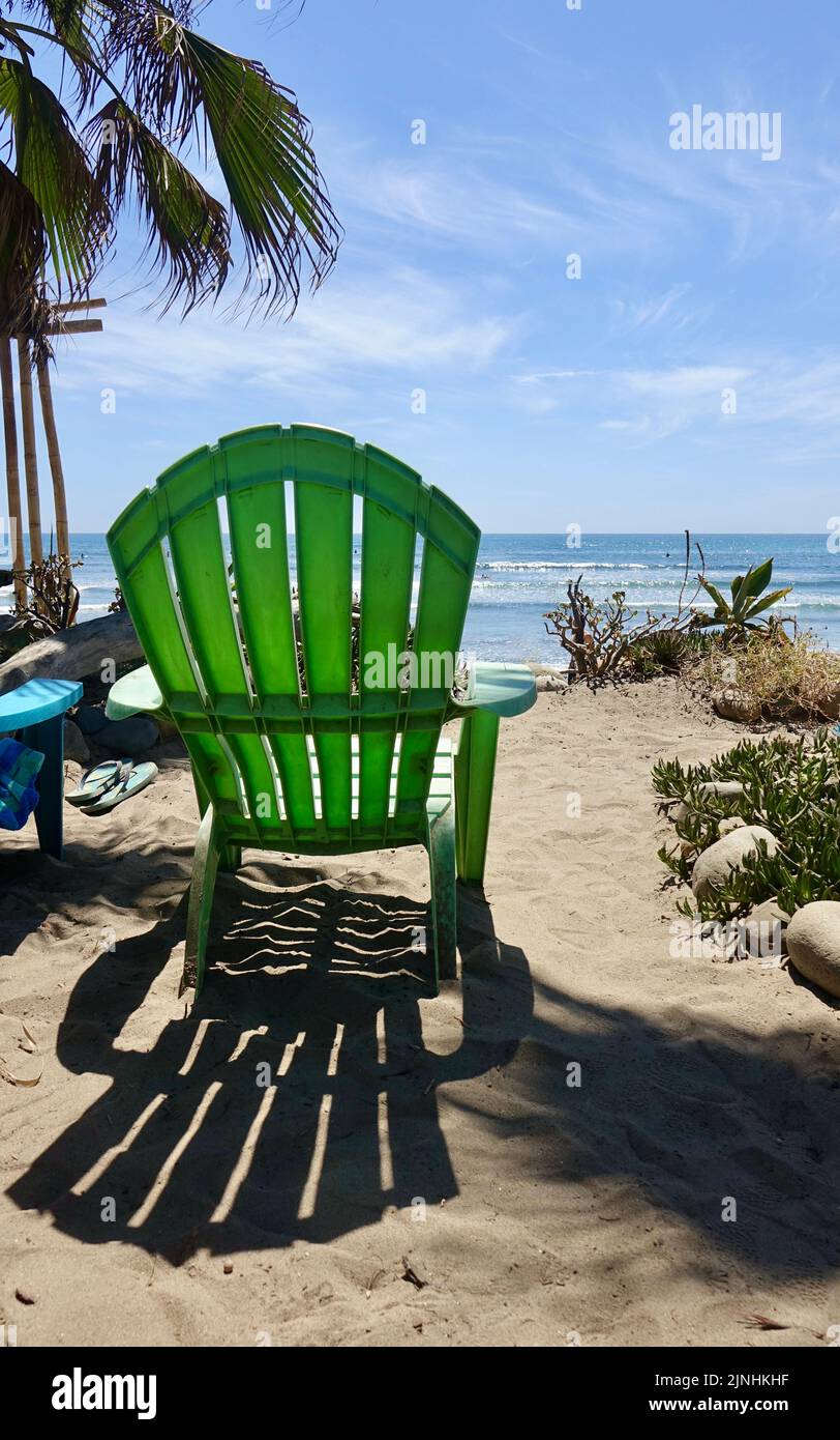Adirondack chair set up to watch surfers from the beach Stock Photo