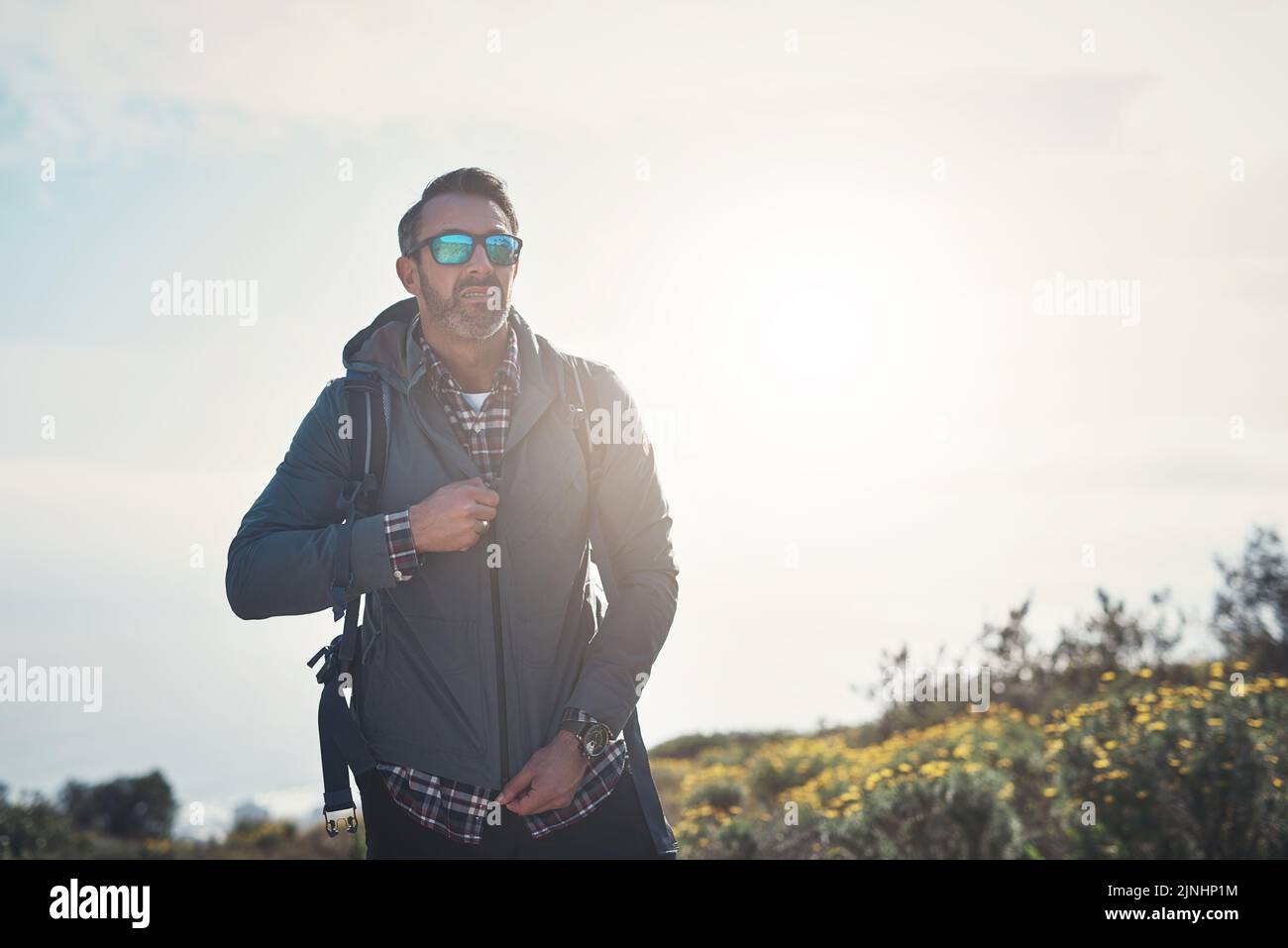 Zip up and keep going. a middle aged man hiking in the mountains. Stock Photo