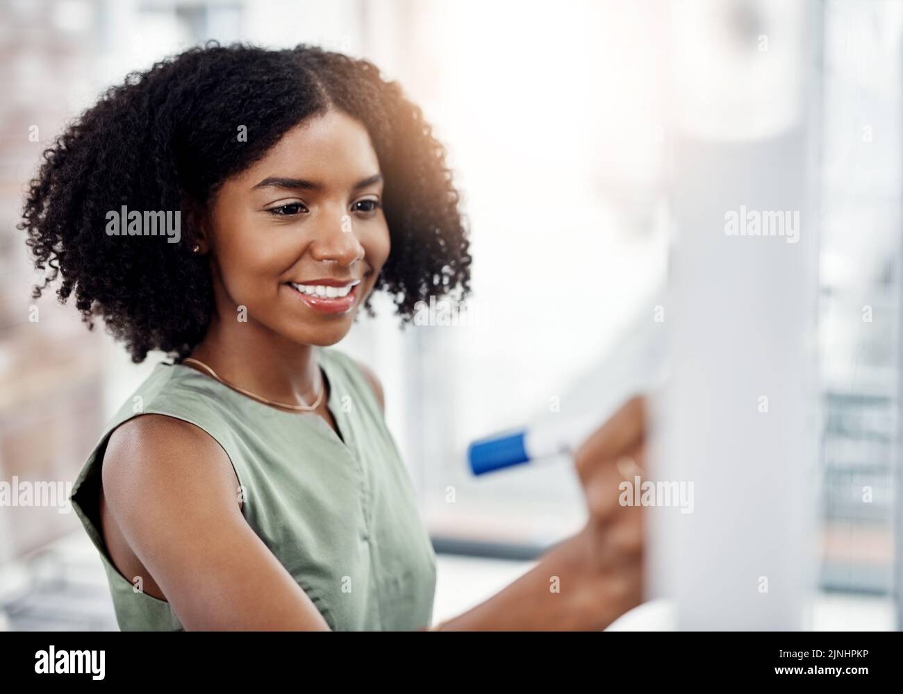 Planning is half the job done. an attractive young businesswoman working on a glass wipe board in her office. Stock Photo