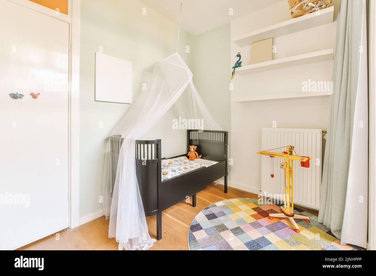 Interior of white room with baby crib near window with blue chest of