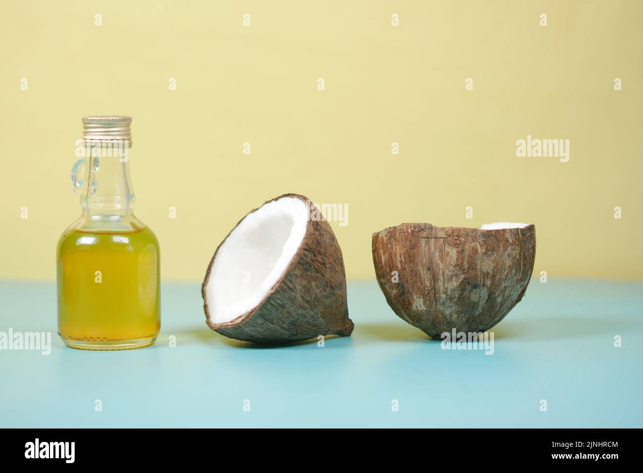 slice of fresh coconut and bottle of oil on a table  Stock Photo