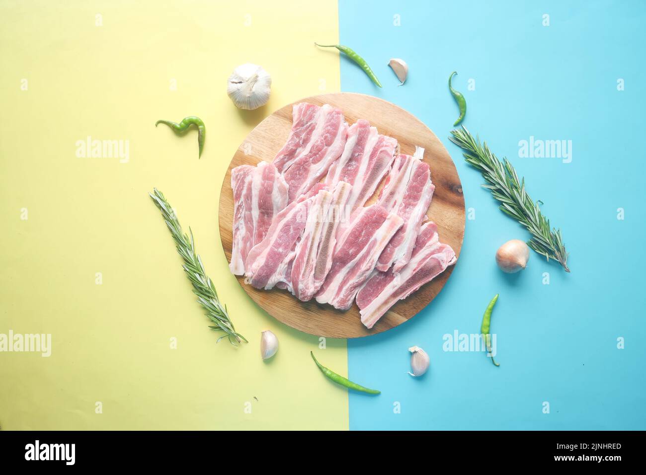 Raw fed bacon strips on chopping board . Stock Photo