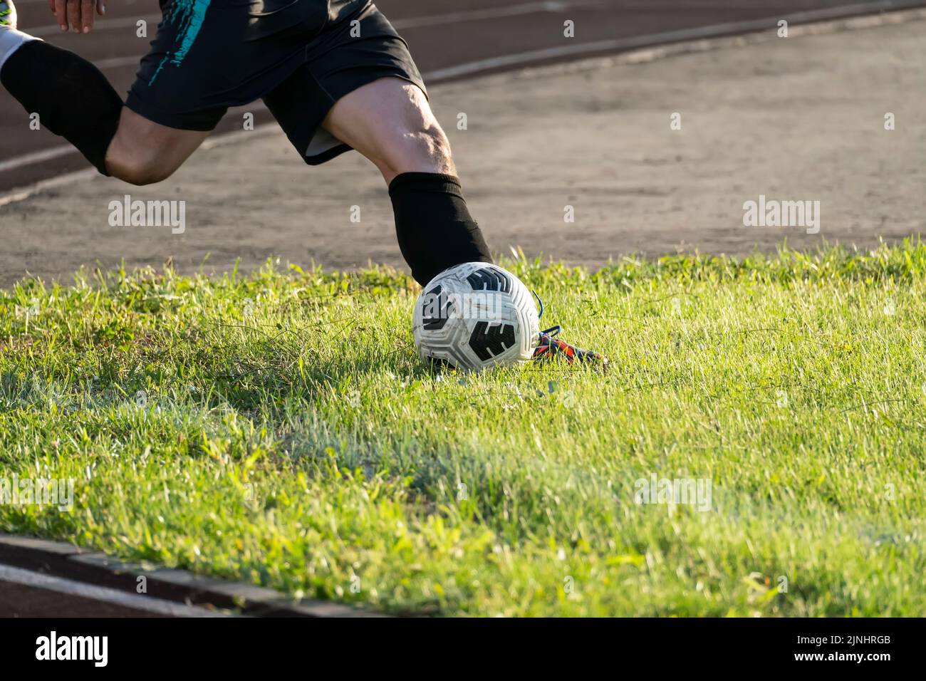 Foot kicking soccer ball on green grass .kick the ball. corner in football Stock Photo
