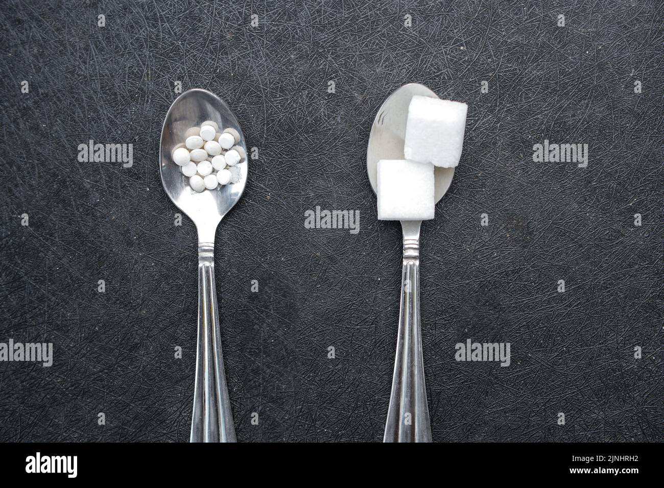 comparing artificial sweetener between raw sweet on a silver spoon  Stock Photo