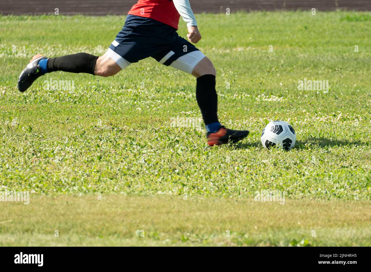 Foot kicking soccer ball on green grass. A free kick on goal in football. Motion into a blur. focus on the ball. Stock Photo