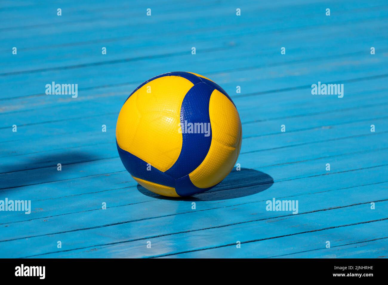 Yellow volleyball on a volleyball court. The floor is made of wood and