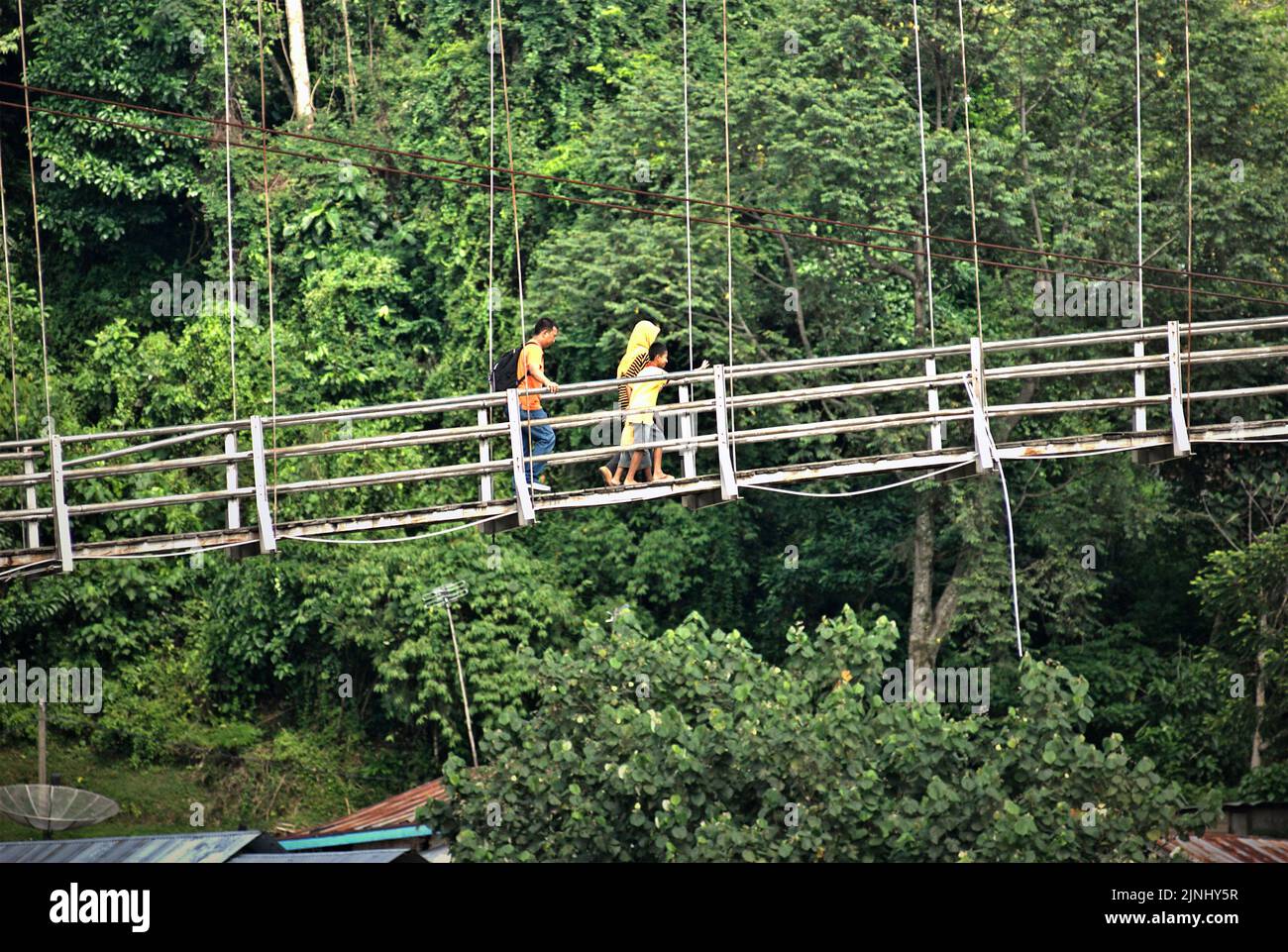 People walking on a hanging bridge, crossing over Bahorok river in Bukit Lawang, Bahorok, Langkat, North Sumatra, Indonesia. Stock Photo
