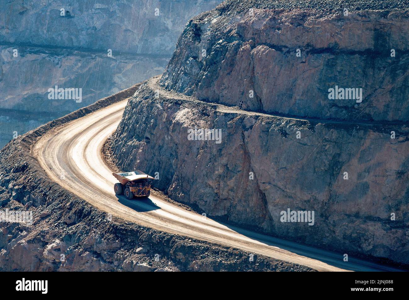 Ore trucks on the road into the Kalgoorlie super-pit gold mine in West Australia, The mining trucks take up to an hour to descend into or drive from the bottom of the pit. Stock Photo