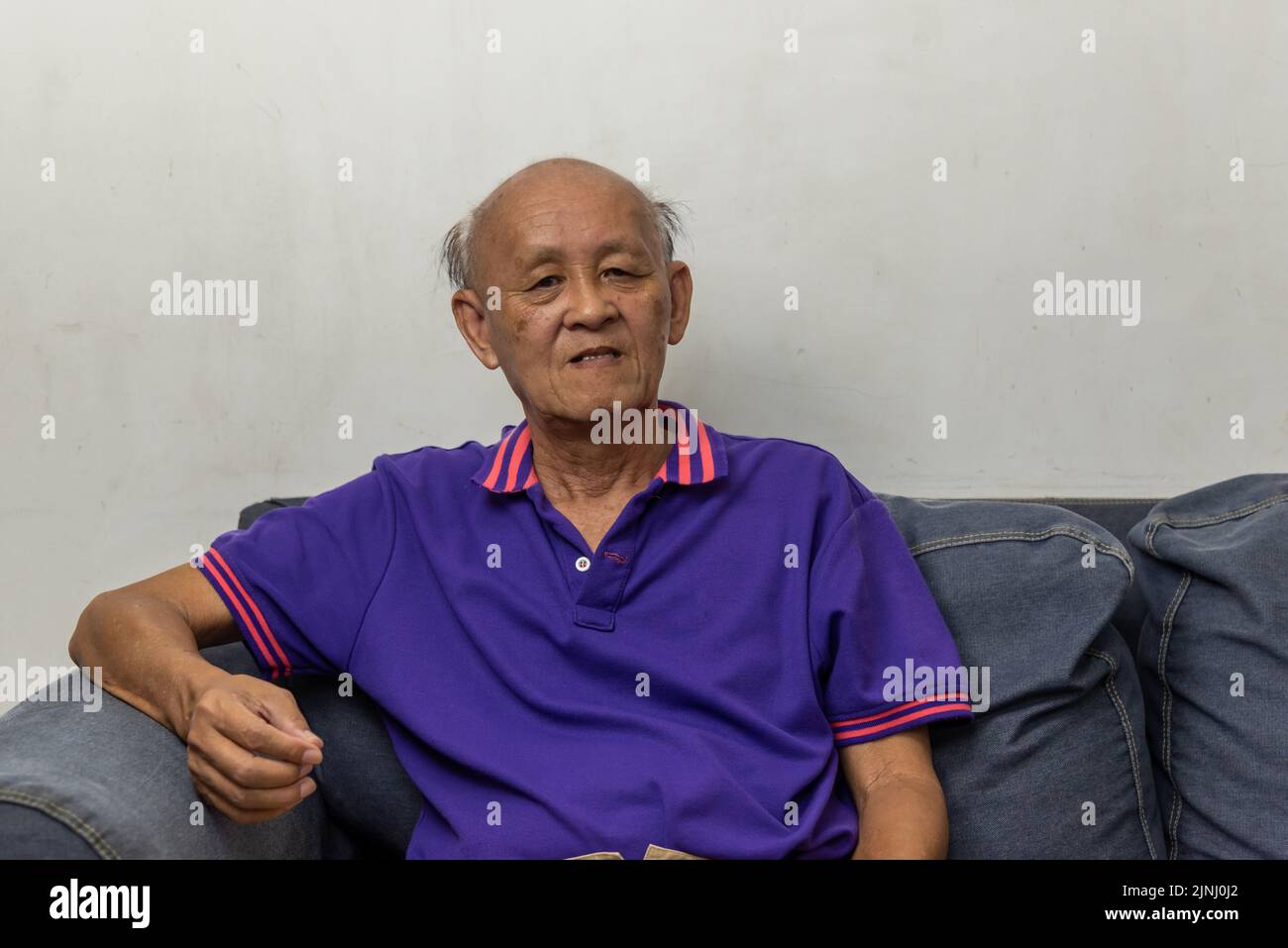 Asian elderly man portrait sitting on the sofa at home. Stock Photo