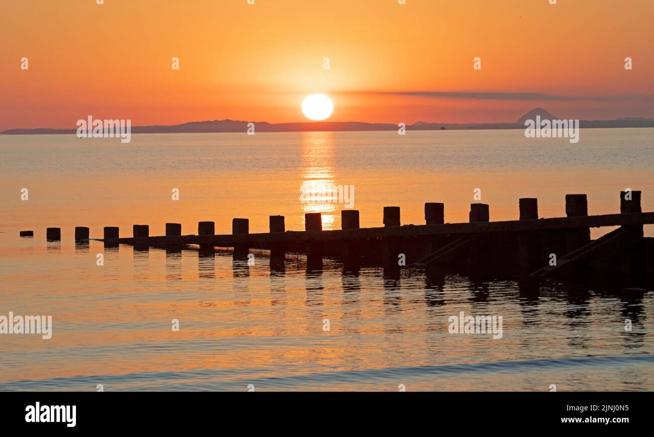 Portobello, Edinburgh, Scotland, UK. 12th August 2022. Stunning sunrise to end a very hot week of above average temperatures for Scotland, temperature this morning at dawn 13 degrees centigrade for those out for exercise at the Firth of Forth seaside.with haar expected later on the east coast.. Credit: Arch White/alamy live news. Stock Photo