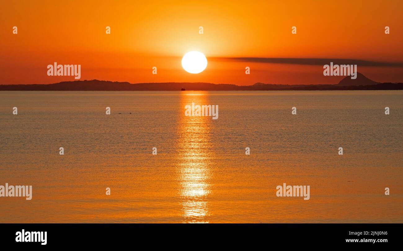 Portobello, Edinburgh, Scotland, UK. 12th August 2022. Stunning sunrise to end a very hot week of above average temperatures for Scotland, temperature this morning at dawn 13 degrees centigrade for those out for exercise at the Firth of Forth seaside.with haar expected later on the east coast.. Credit: Arch White/alamy live news. Stock Photo