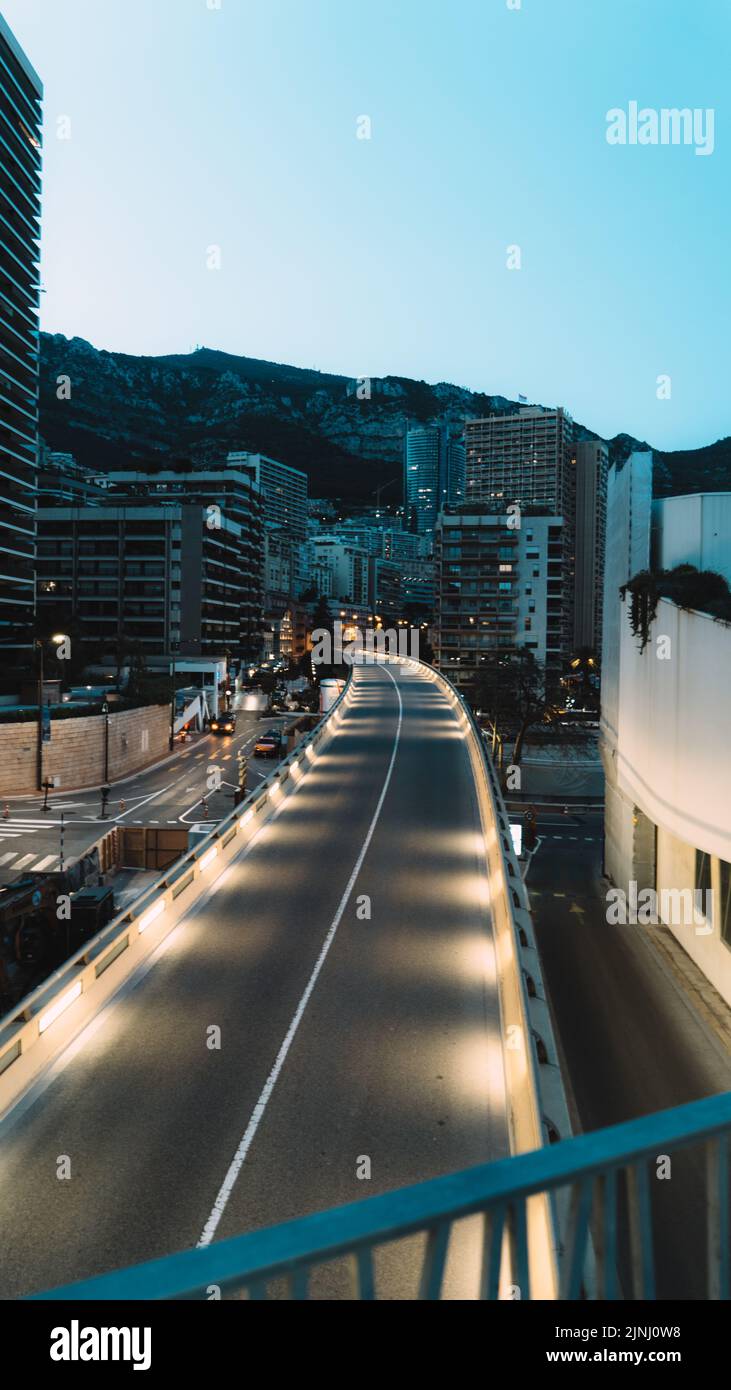 A vertical shot of a highway with illuminated lights and high-rise ...