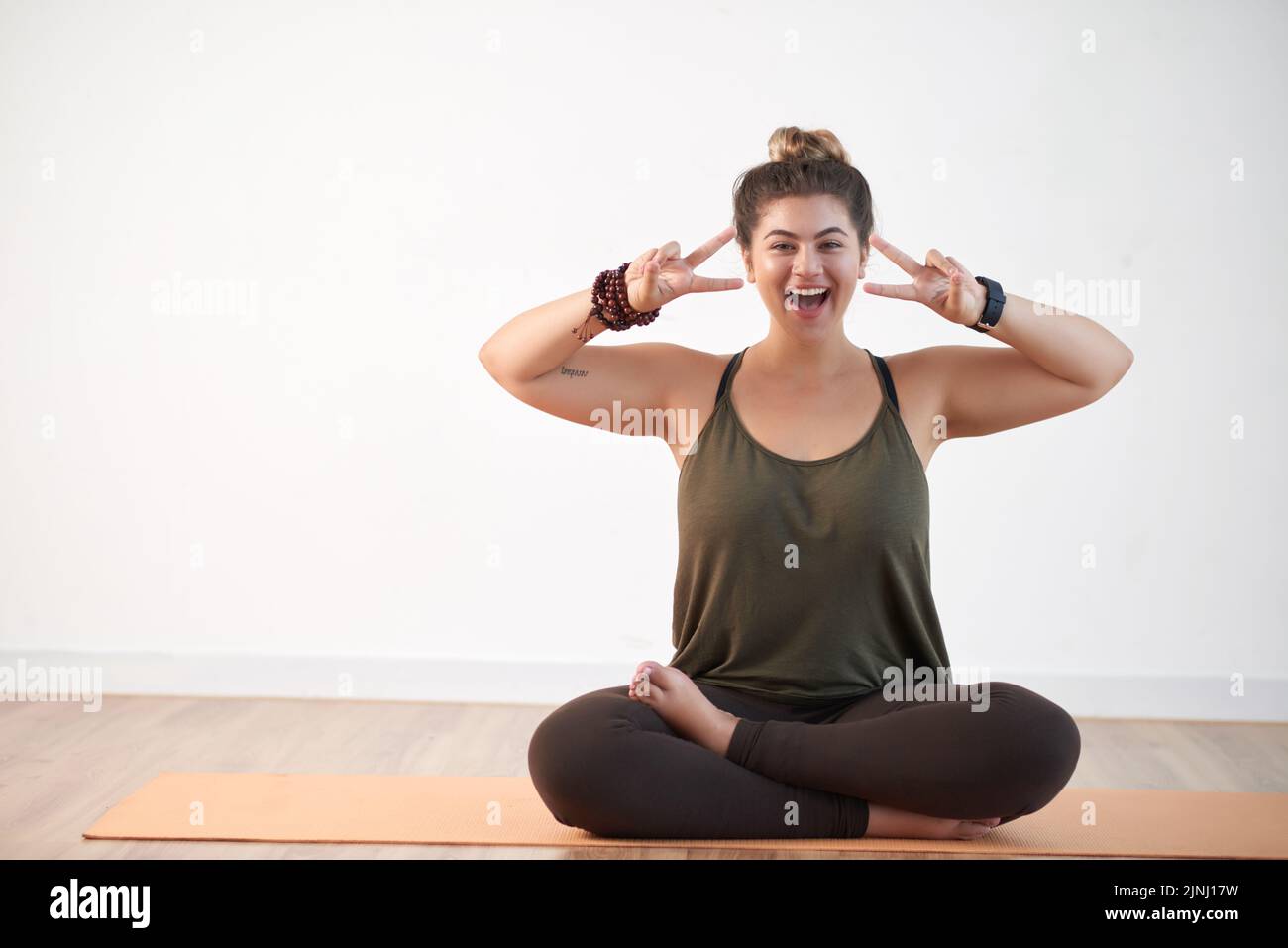 Victory Position Attractive young woman wearing leggings and top showing victory gesture ...