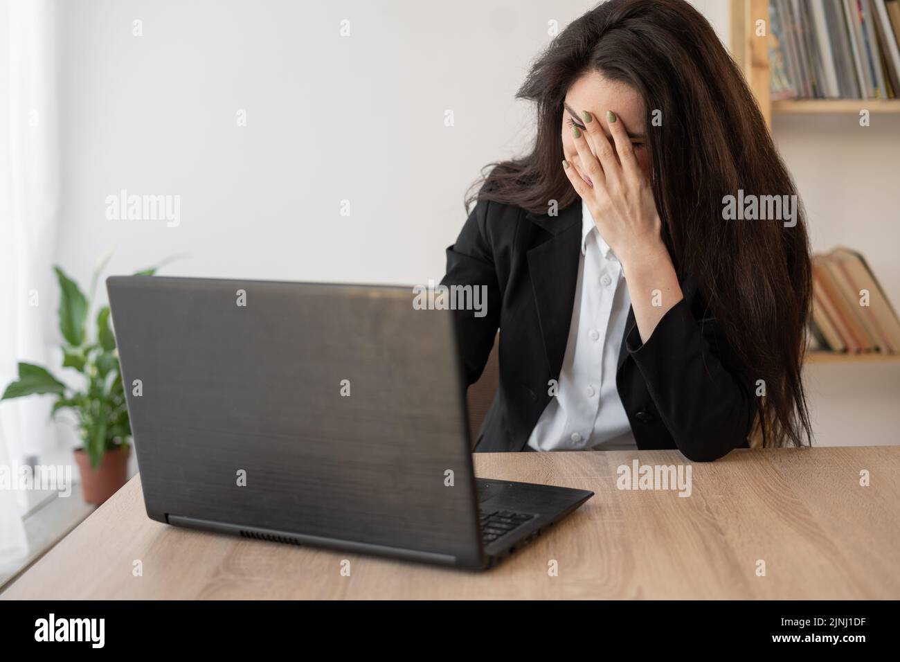 Woman working on laptop in office having a headache, migraine, relieving stress, chronic pain, help to calm. chronic fatigue syndrome Stock Photo