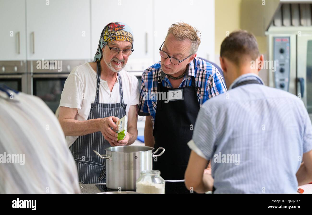 PRODUCTION - 30 June 2022, Lower Saxony, Lüneburg: Winfried Marx, professional chef (l), gives Jörg cooking tips at the cooking group for grieving widowers. The members of the small group, which meets once a month in Lüneburg to cook, are between 59 and 87 years old. A professional guides the widowers. (to dpa-KORR "Cooking group for grieving widowers - ready meals are taboo") Photo: Philipp Schulze/dpa Stock Photo