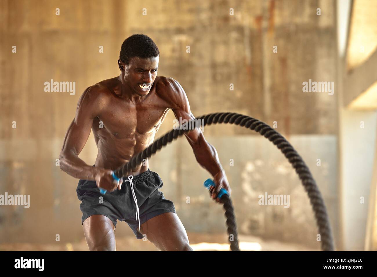 Rope workout. Sport man doing battle ropes exercise outdoor. Black male athlete exercising