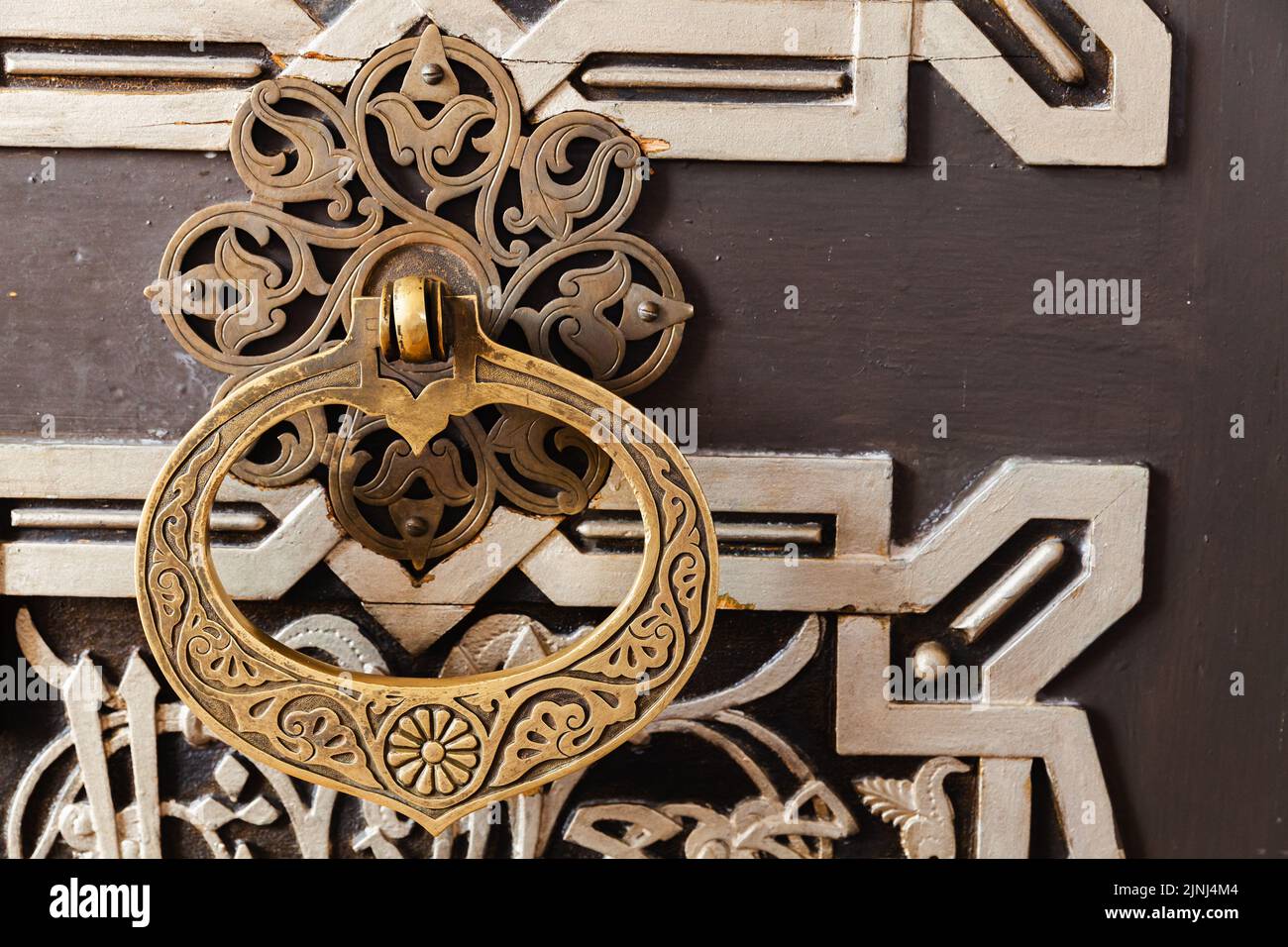 Vintage handle on an old oriental wooden door decorated with ornaments Stock Photo