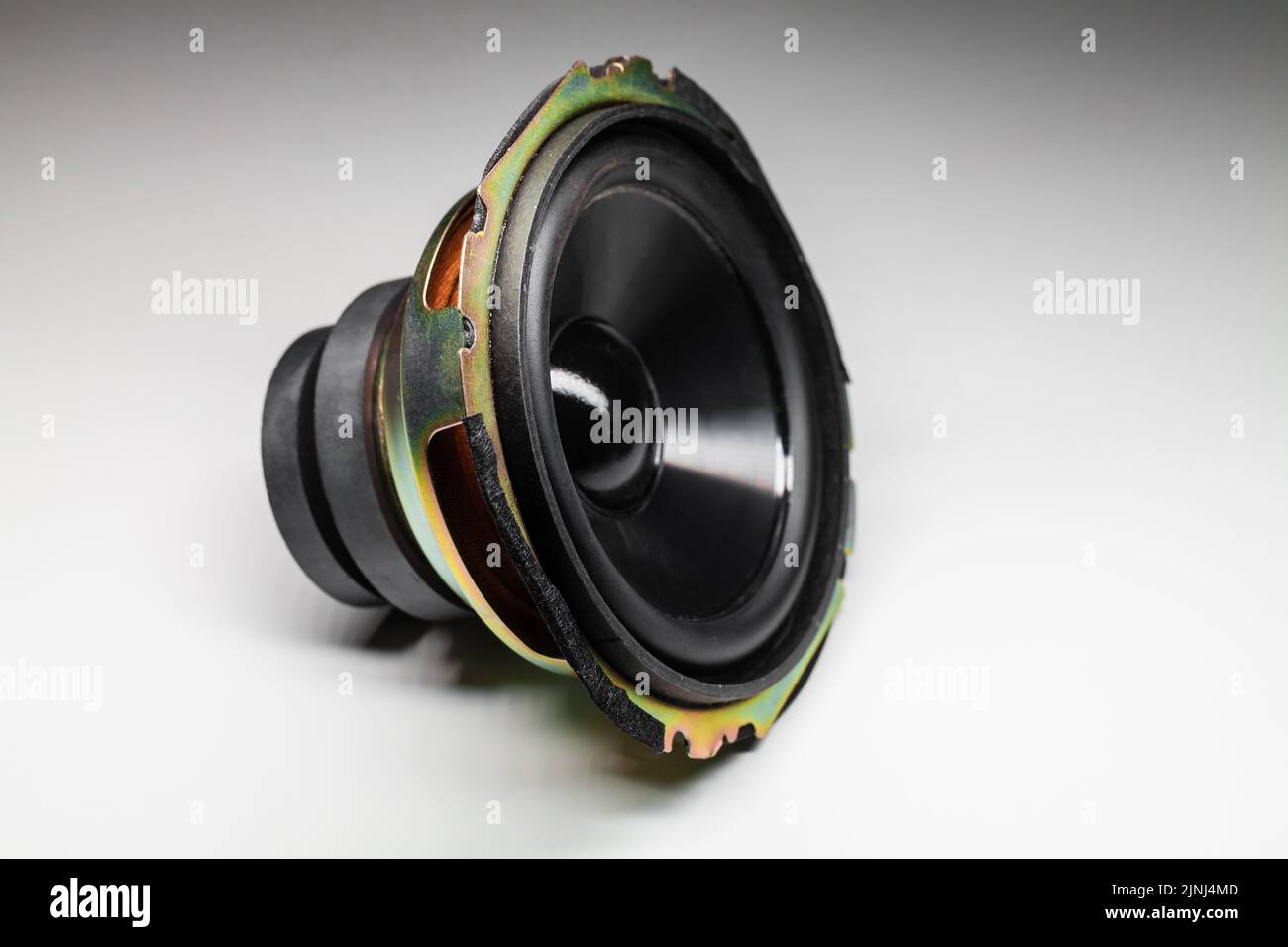 Shiny black woofer, audio speaker lays on a white background with soft