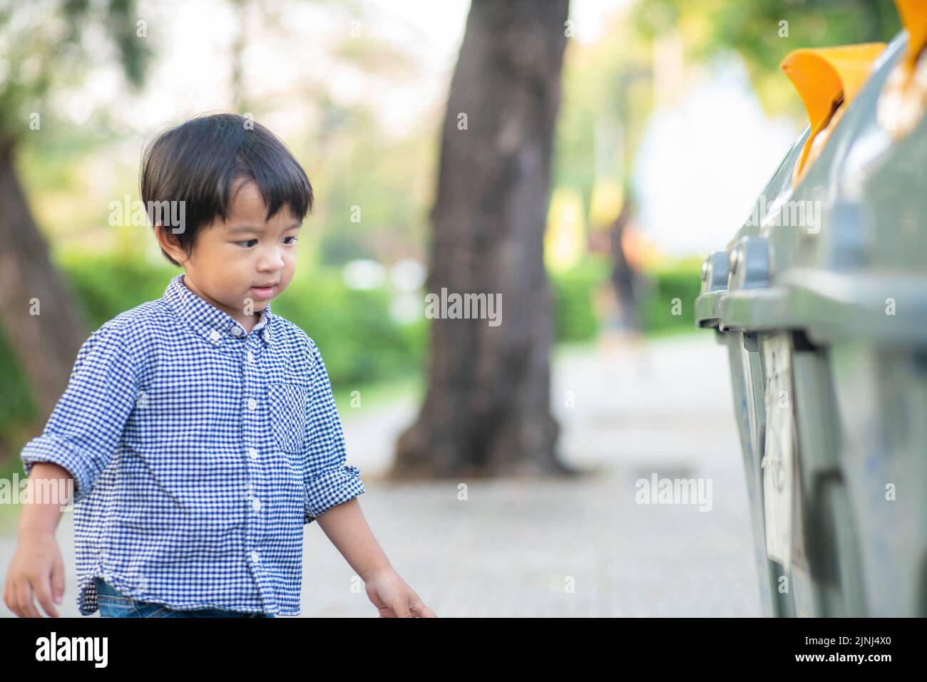 Boy keep litter garbage into bin in city park keep clean concept Stock Photo