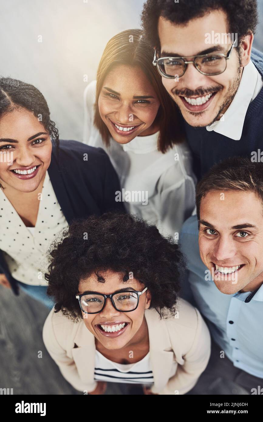 Diverse group of creative colleagues from above looking excited, happy or motivated and ready to take startup business to the top. Portrait of smiling Stock Photo