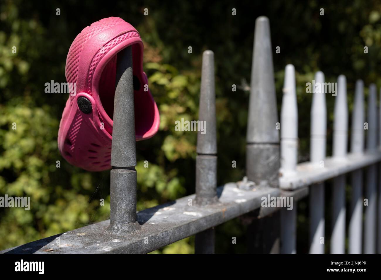 A single child's pink Croc shoe rests on some railings outside Ruskin Park, on 10th August 2022, in London, England. Stock Photo