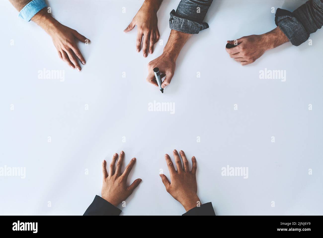 Business people writing on white paper in meeting, planning a marketing strategy and writing creative ideas together from above. Top view of hands of Stock Photo
