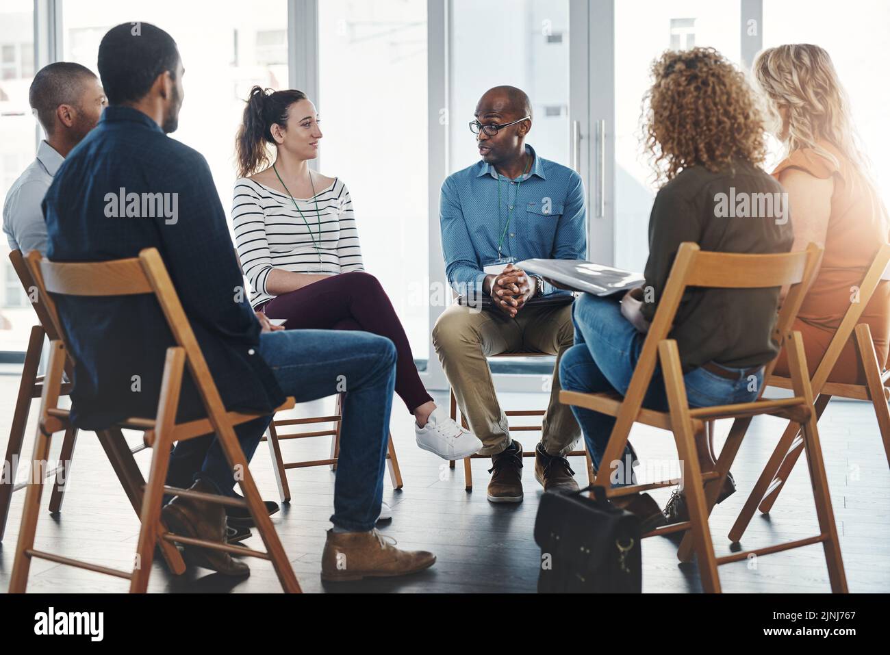 A group therapy session with diverse people sharing their sad problems and stories. People sitting in a circle talking about their mental health Stock Photo