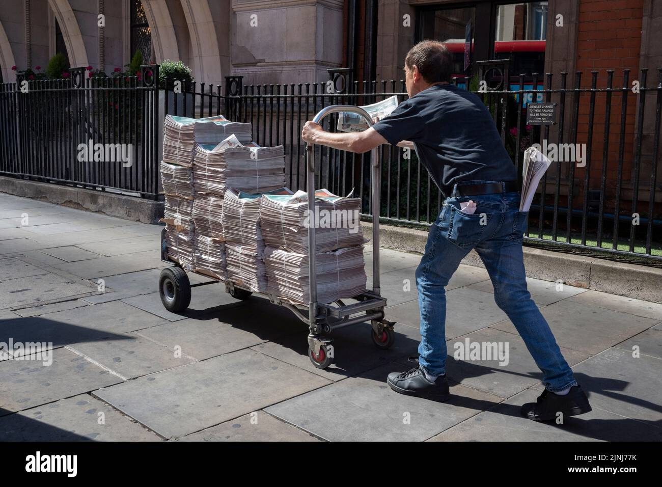 An Evening Standard newspaper vendor pushes a cart full of newspring copies in the City of London, the capital's financial district (aka the Square Mille), on 10th August 2022, in London, England. Stock Photo