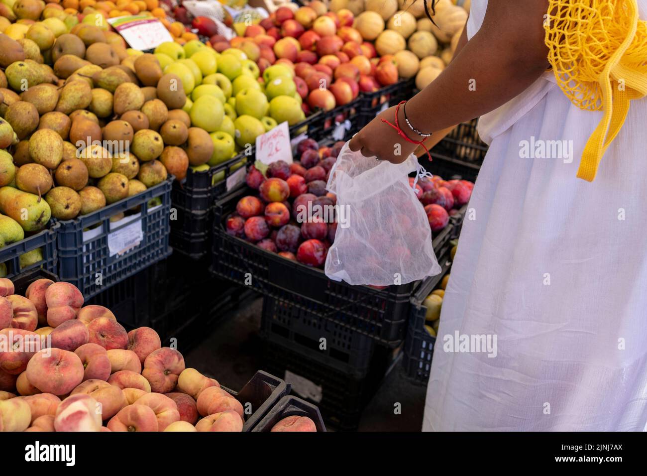 Female hands puts fruits and vegetables in cotton produce bag at food market. Reusable eco bag for shopping. Zero waste concept. Stock Photo