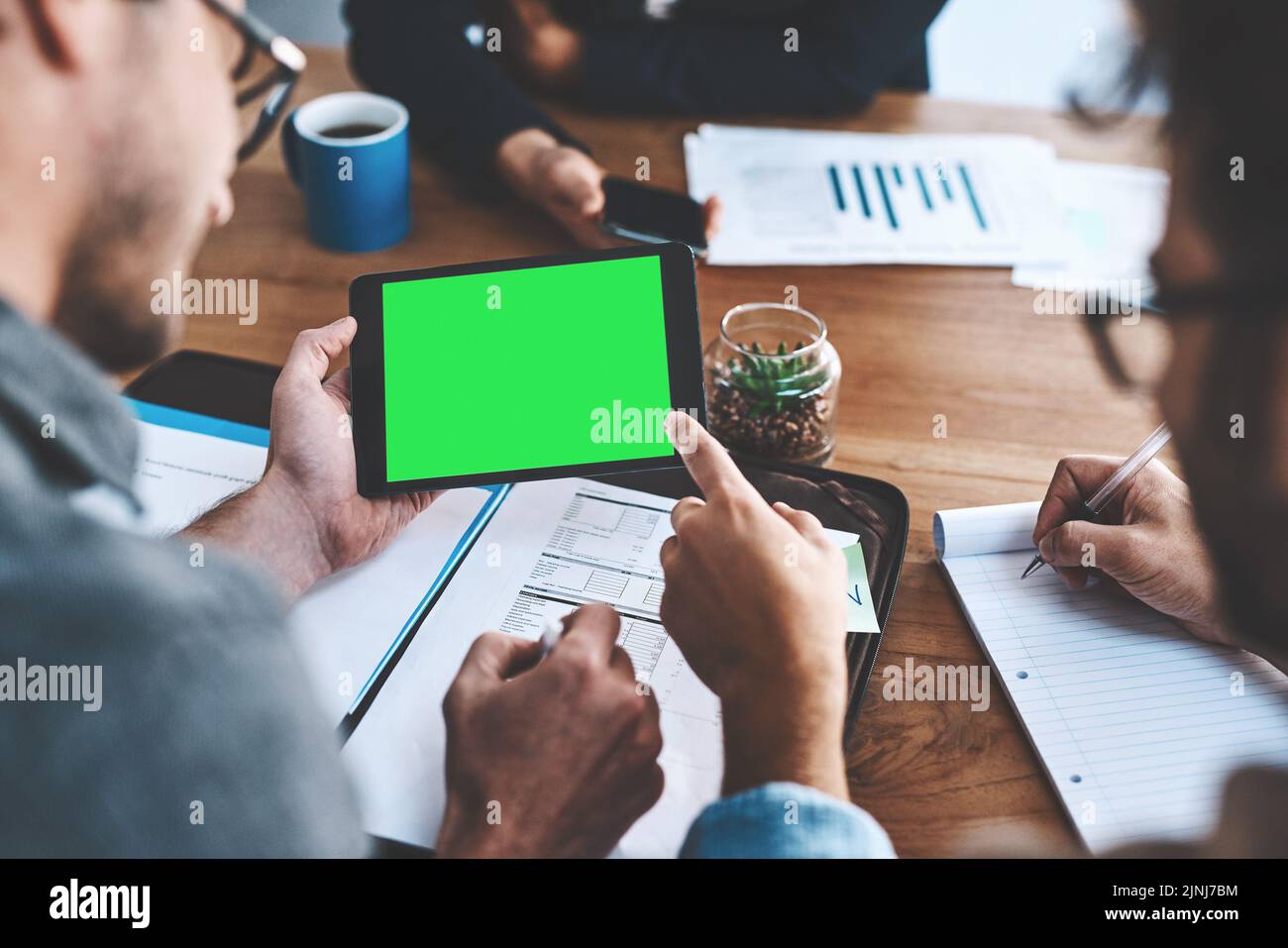 Green screen, copyspace and chromakey on a tablet screen in the hands of a business man in a meeting in a boardroom. Advertising, marketing and online Stock Photo