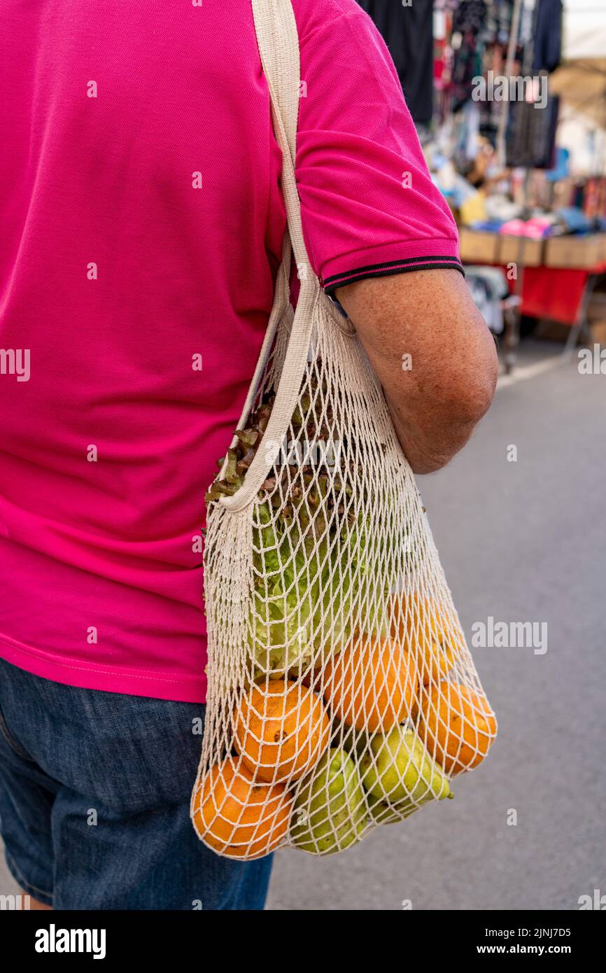 man carrying reusable mesh bag after shopping food market, Sustainable lifestyle with zero waste and plastic free shopping concept Stock Photo