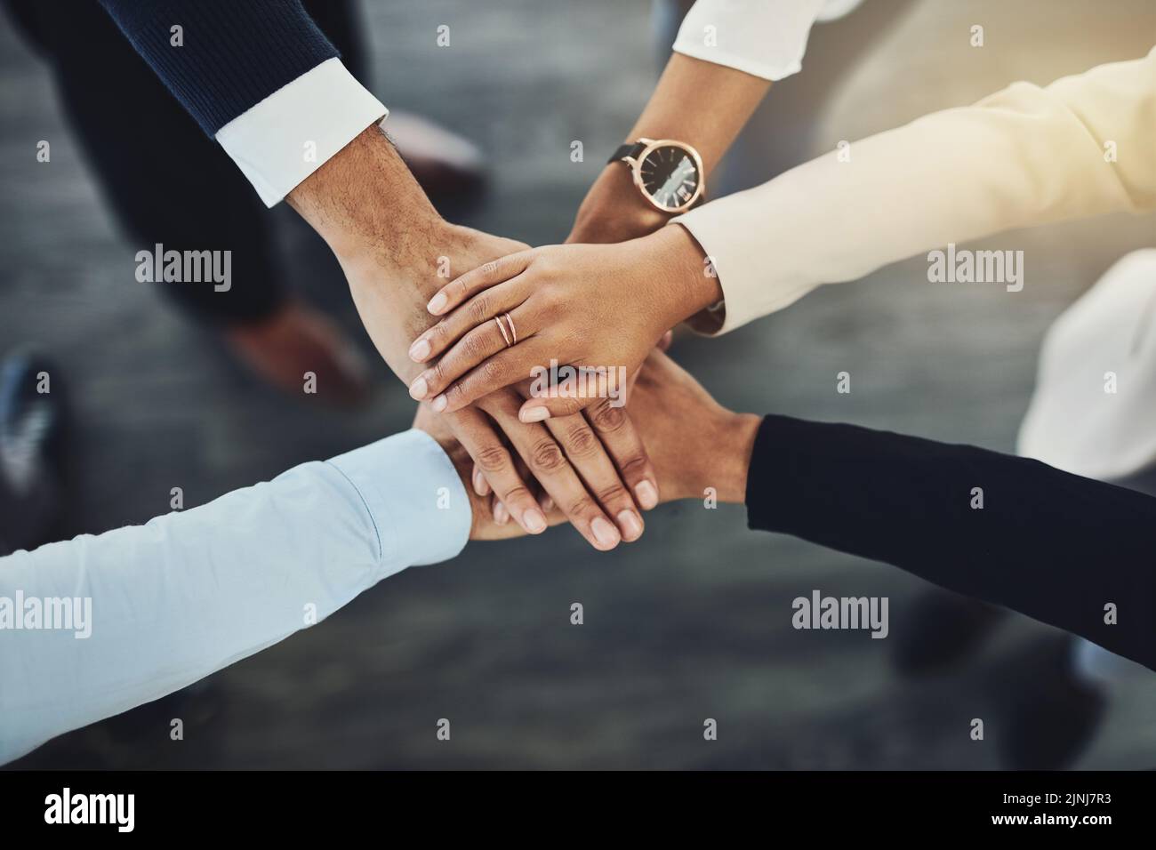 Hands stacked or piled to show team unity, strength or motivation among business men, women or colleagues from above. Closeup of huddled, motivated Stock Photo