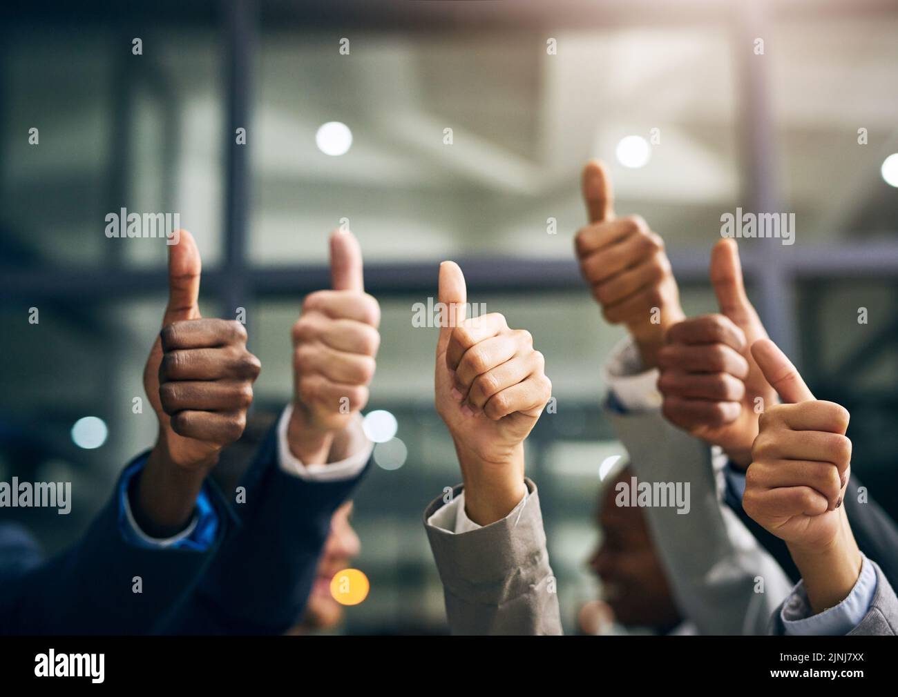 Hands showing thumbs up with business men endorsing, giving approval or saying thank you as a team in the office. Closeup of corporate professionals Stock Photo