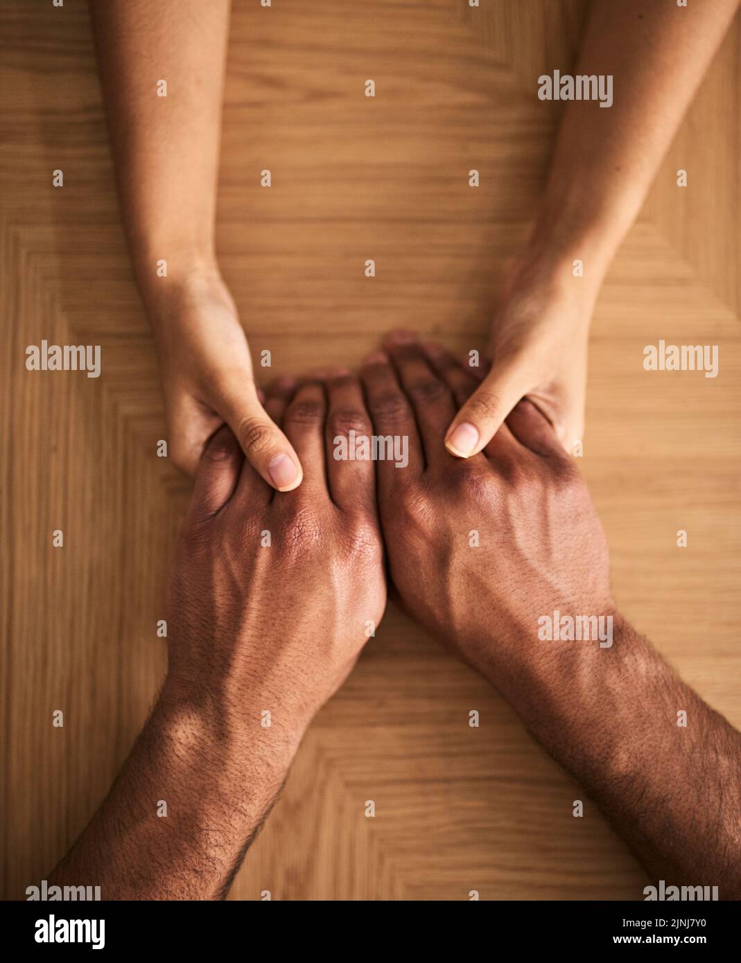 Man and woman holding hands sharing feelings of love, support and trust together on a table. Closeup of a loving couple expressing care, promise and Stock Photo