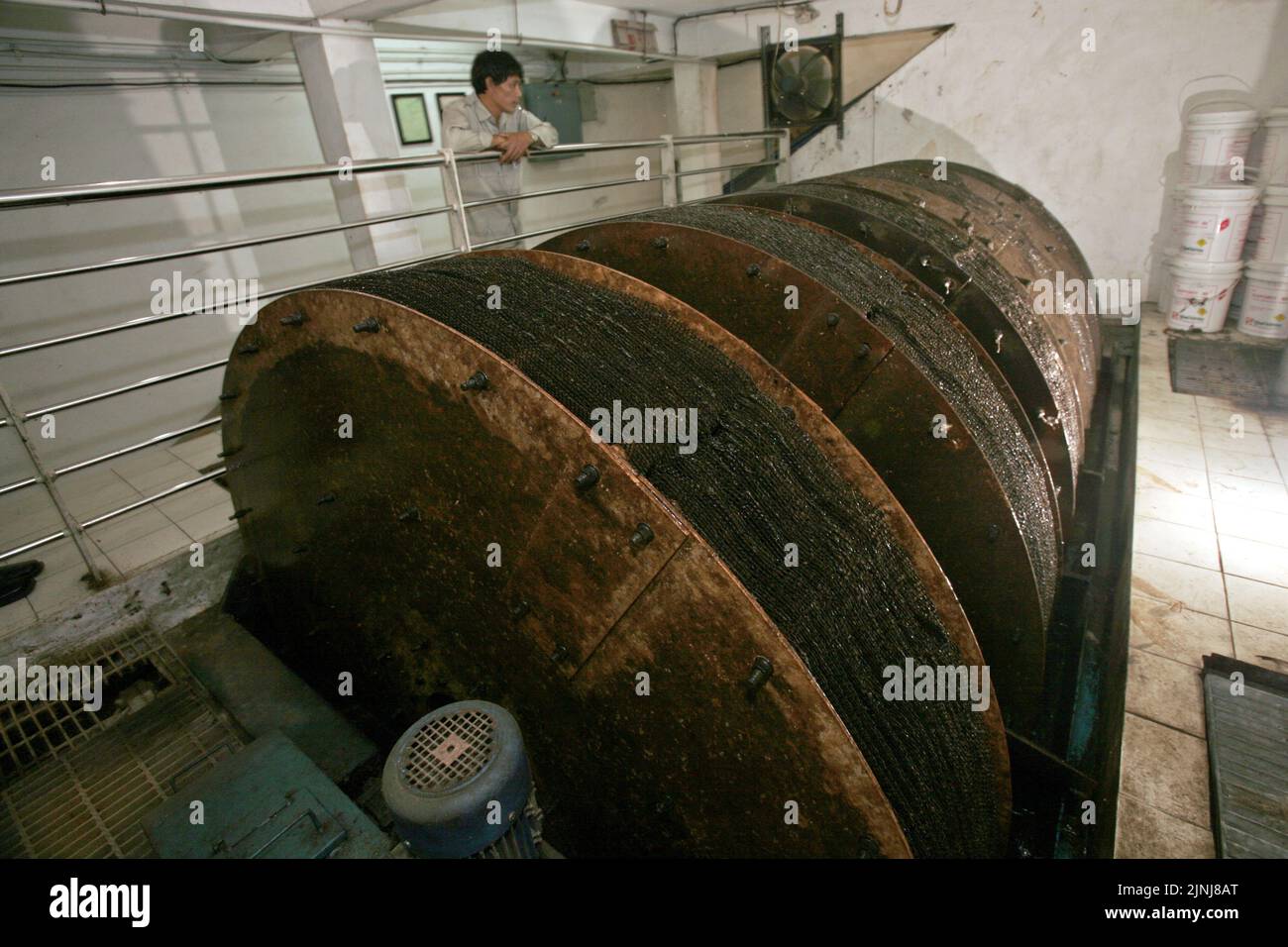 A worker is photographed as he is standing behind an installation of wastewater recycling system at Kompas Gramedia building in Kebon Jeruk, West Jakarta, Jakarta, Indonesia. Stock Photo