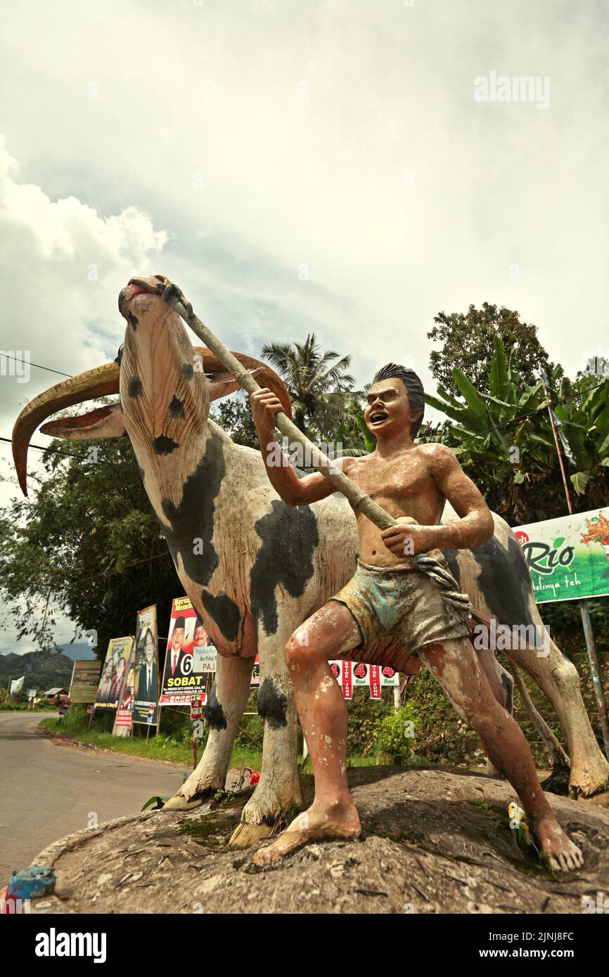 Statue of a man leading a 'tedong bonga' (white buffalo with black spots) that is considered as a very valuable cow breed among the traditional communities in Toraja, photographed in Rantepao, North Toraja, South Sulawesi, Indonesia. Stock Photo