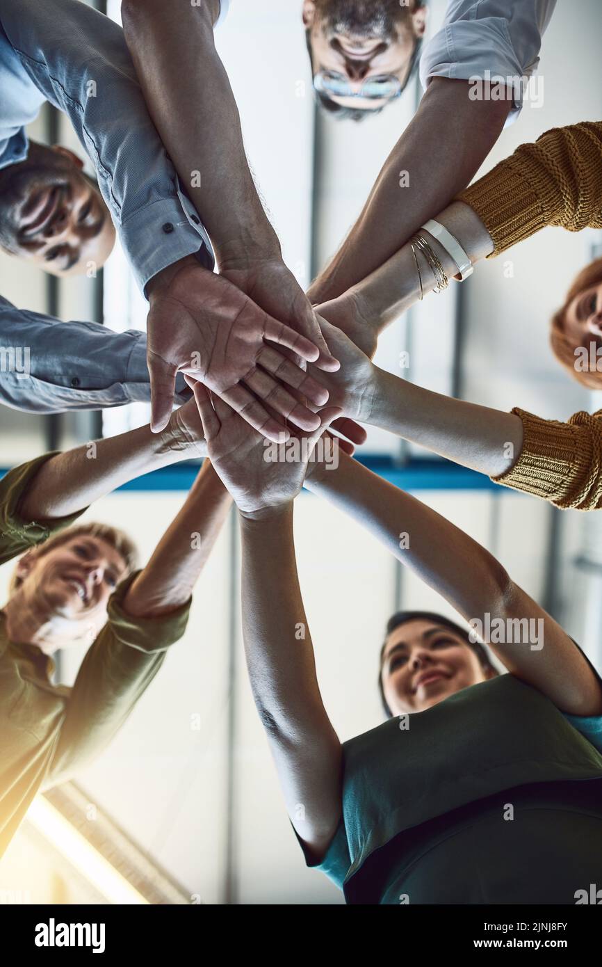 Winning, celebrating and successful business people stack hands in the office for team building. Group of employees in agreement on unity, help and Stock Photo