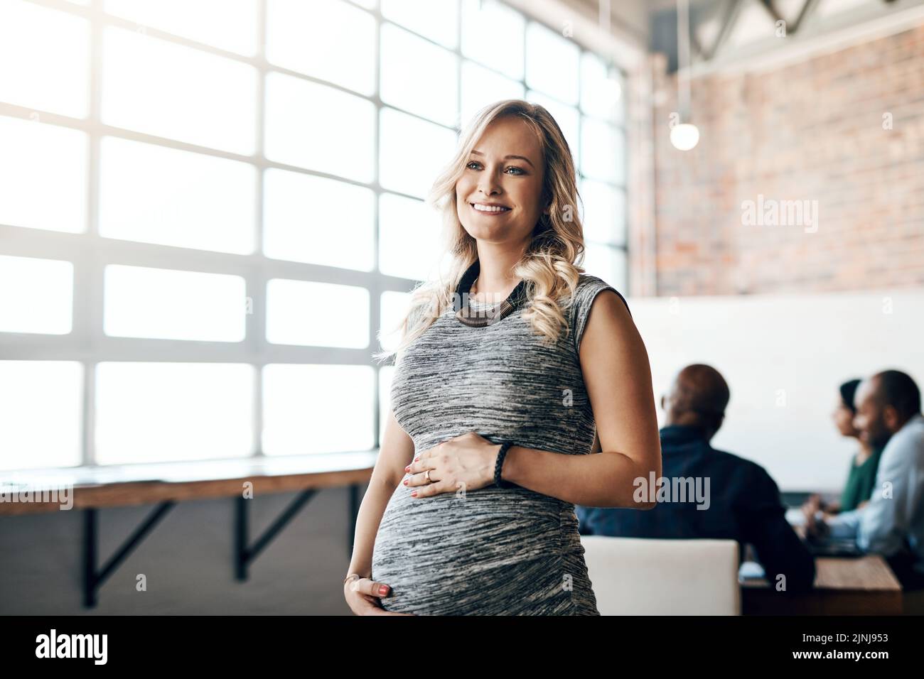 Pregnant business woman leader, working and smiling in a modern office during a meeting. Having one last meeting before her maternity leave starts Stock Photo